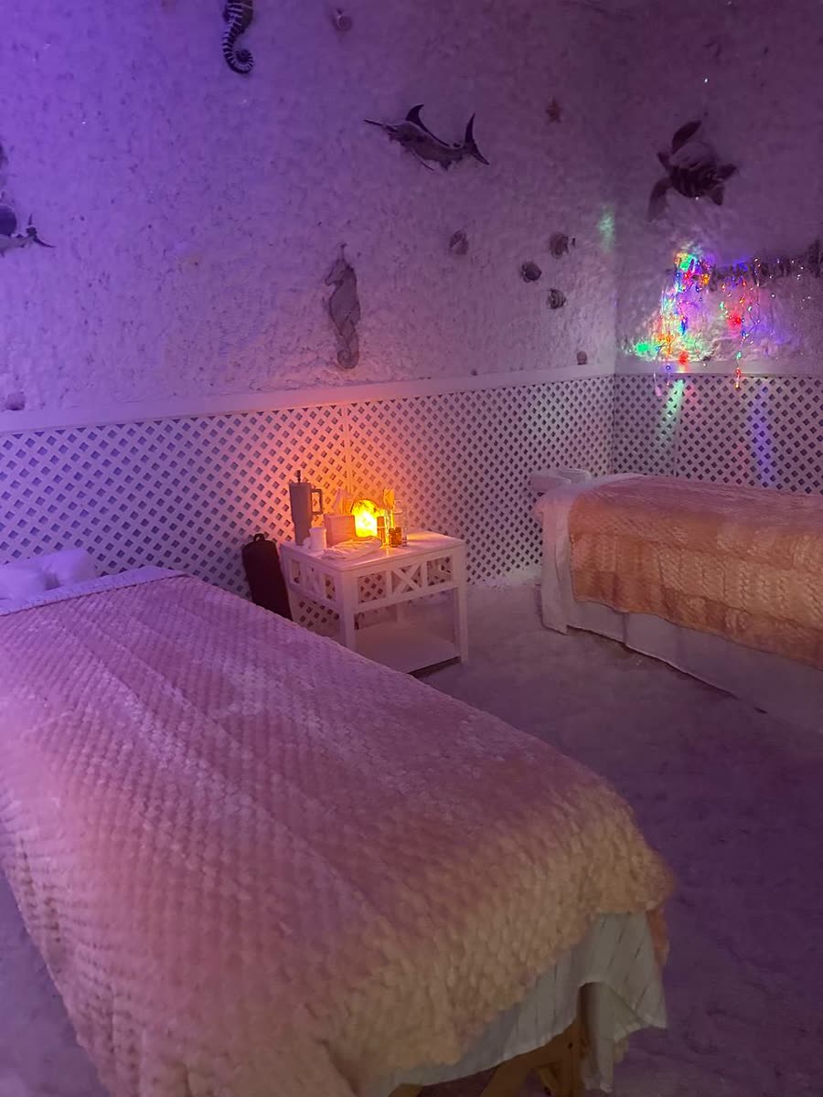 Two massage tables set side by side inside the Small Salt Cave at Salinair Salt Room Spa, salt walls glowing under soft light